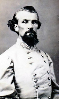 An old black and white picture showing the first leader of the KKK Nathan Bedford Forrest loking proud from the waist up in his military uniform, he has a large bushy beard and slicked back hair with a stern expression on his face